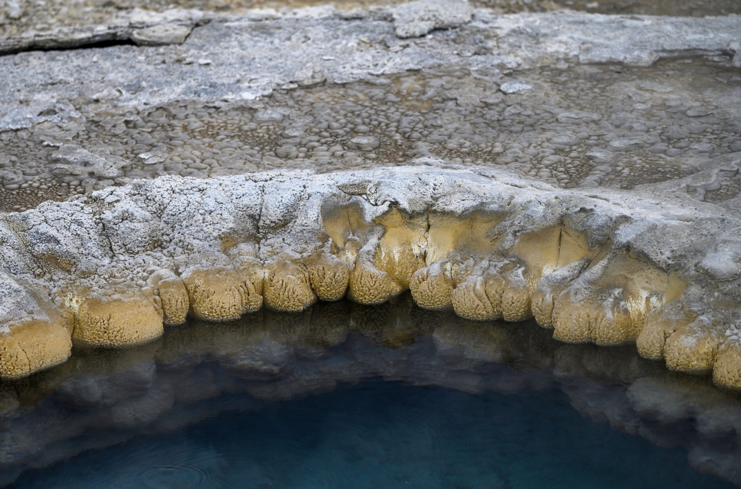 Close-up of a natural rock formation surrounding a geothermal pool with unique textures.