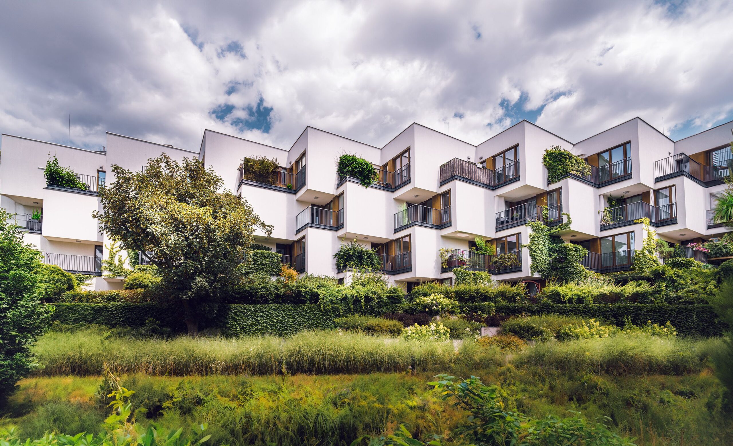 Contemporary apartment complex featuring sustainable architecture with lush greenery and open balconies.