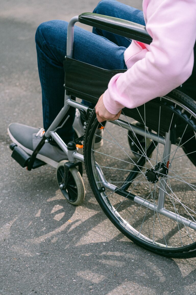 Close-up of an adult managing a wheelchair outdoors on a sunny day, emphasizing independence.